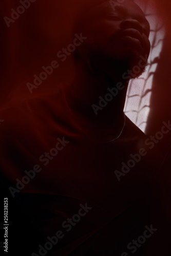 Art portrait of black man posing behind red fabric. Sensual. Art performance, acting.