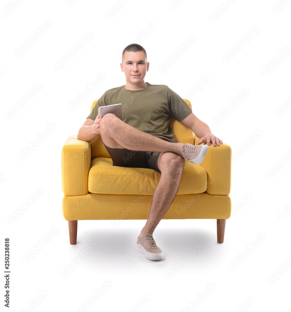 Young man with tablet computer sitting in armchair against white background Young man with tablet computer sitting in armchair against white background