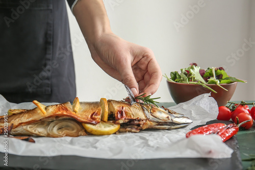 Woman decorating tasty mackerel fish at table, closeup