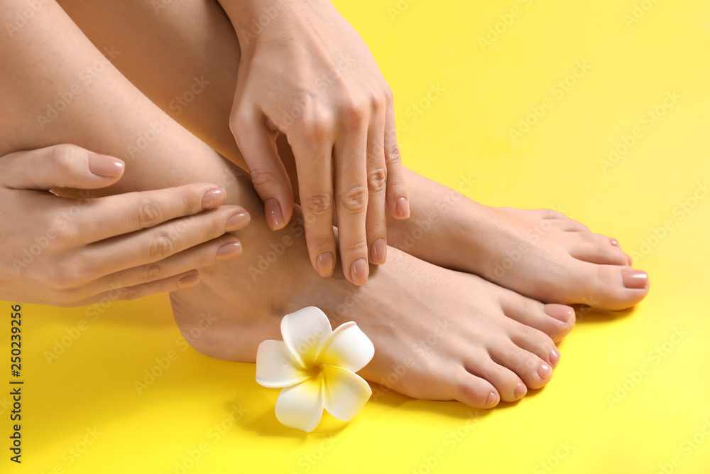 Legs and hands of young woman with beautiful pedicure and manicure on color background