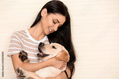 Portrait of young woman with her cute labrador dog on light background © Pixel-Shot