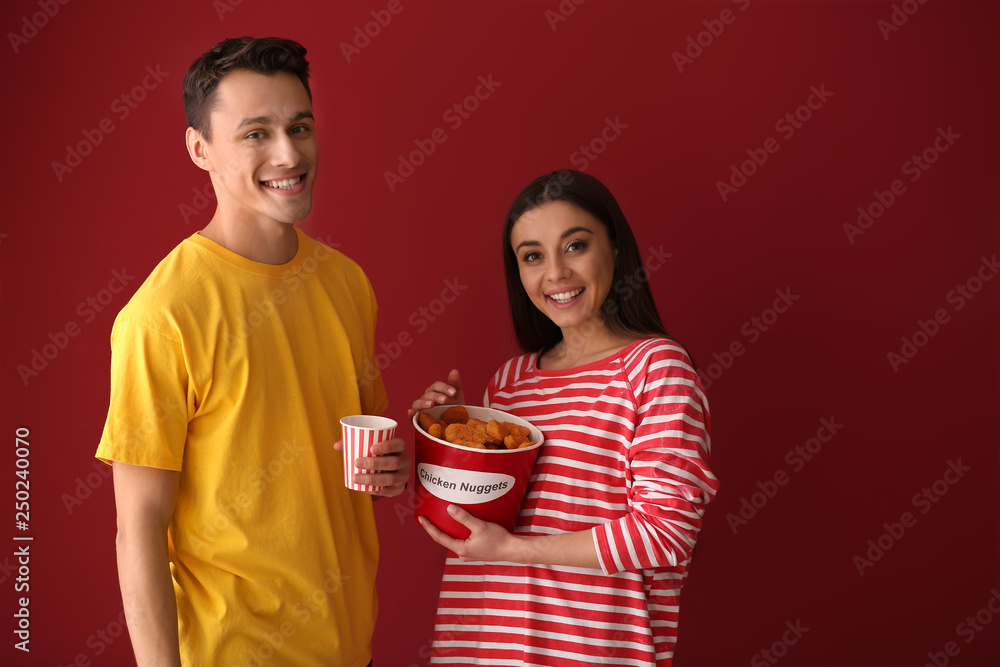 Friends with bucket of nuggets and drink on color background Friends with bucket of nuggets and drink on color background