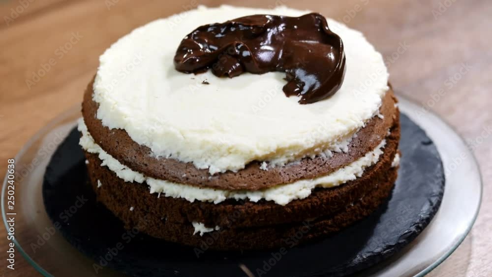 Chocolate ganache icing on cake. Close up of biscuit cake homemade dessert decoration. Female baker decorating and shaping cake. Chocolate ganache icing on cake. Close up of biscuit cake homemade dessert decoration. Female baker decorating and shaping cake.