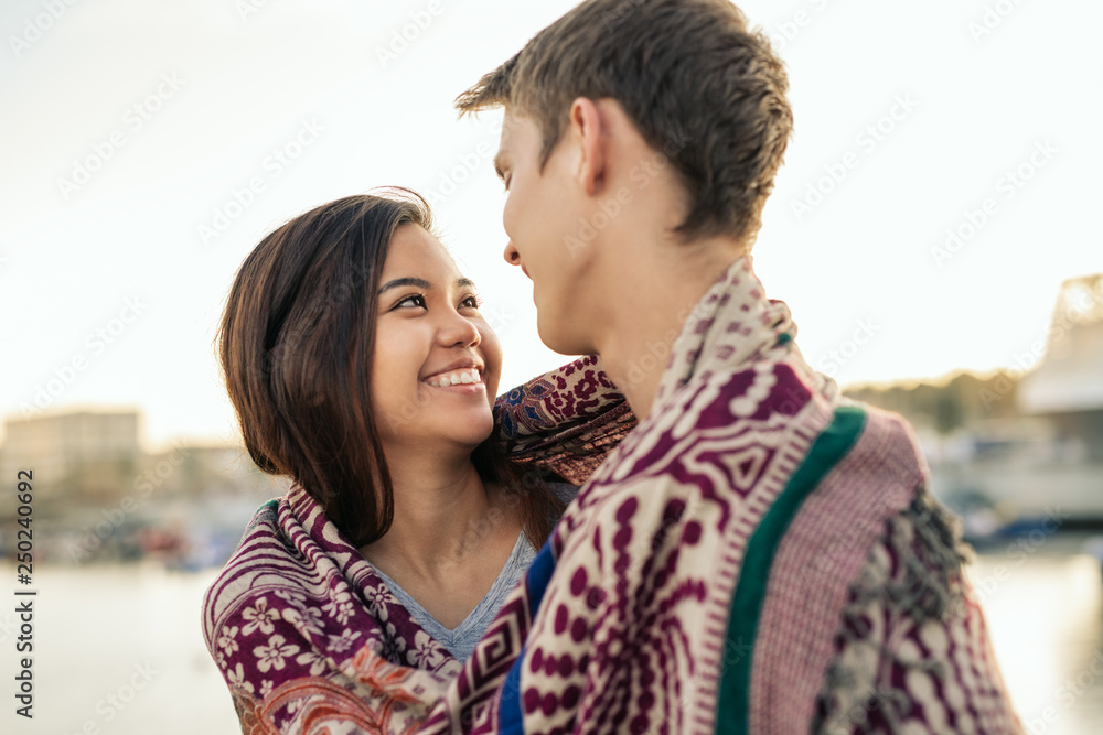 Young couple smiling while wrapped in a blanket together outside Young couple smiling while wrapped in a blanket together outside