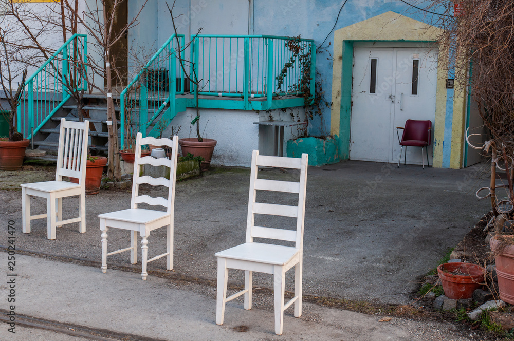 three white chairs infront of blue house three white chairs infront of blue house