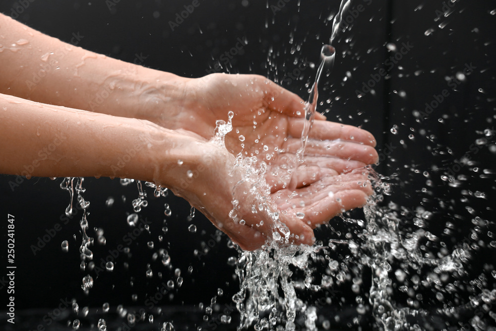 Woman washing hands on dark background Woman washing hands on dark background