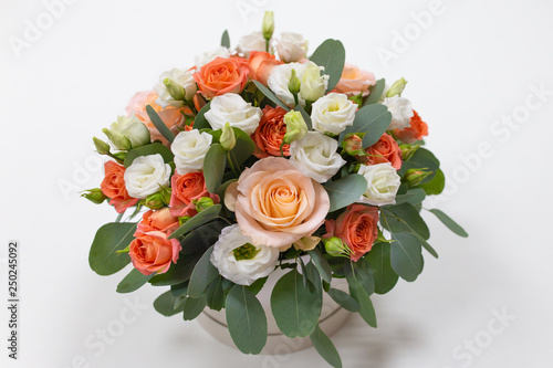 An impressive composition of roses and Eucalyptus leaves in a hat box  color  pink  pink  orange  green  on a light background