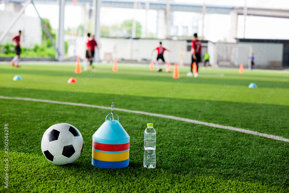 soccer ball, marker cones and bottle water on green artificial turf soccer ball, marker cones and bottle water on green artificial turf
