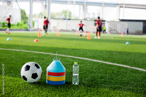 soccer ball, marker cones and bottle water on green artificial turf