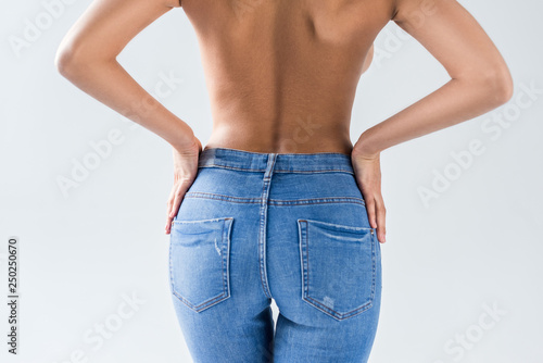 Cropped view of nude sexy woman in jeans on grey background