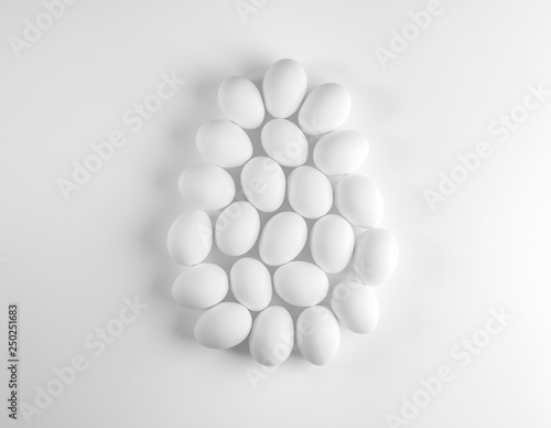 White chicken eggs laid out as large egg on white background.