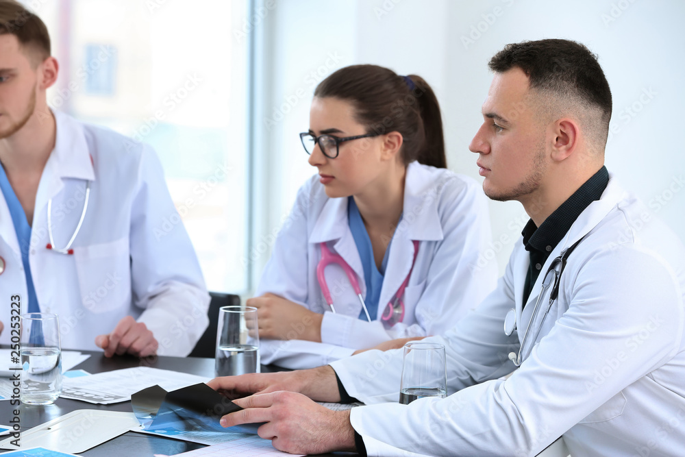 Obraz premium Team of doctors discussing diagnosis at table in clinic