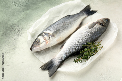 Tasty fresh seabass fish with thyme on light background