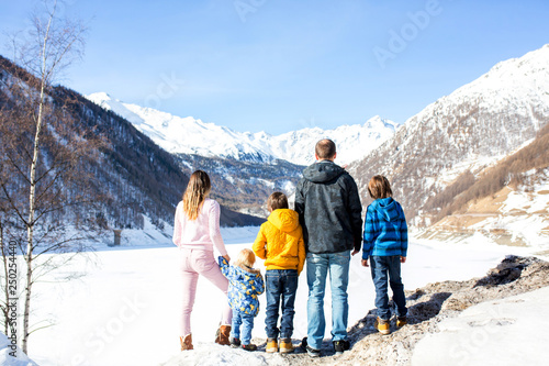 Family, enjoying winter view of snowy mountains and frozen lake