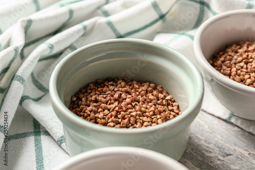 Bowls with raw buckwheat on wooden table
