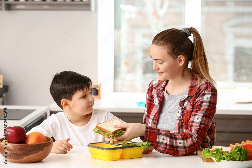 Mother packing school lunch for her little son at home Mother packing school lunch for her little son at home