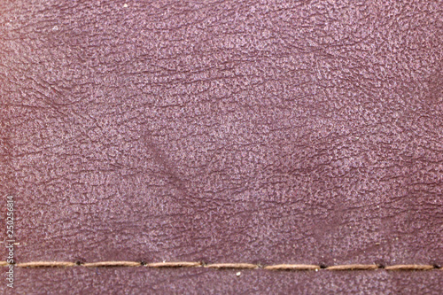 texture of red old leather with a seam of thread