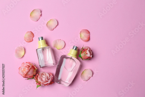 Bottles of perfume and flowers on color background