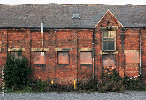 Vászonkép An old abandoned brick factory building with boarded up windows and crumbling de