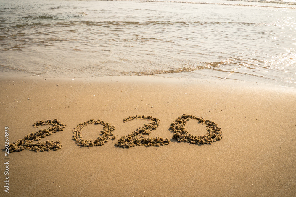 Fototapeta premium Happy New Year 2020 concept, 2020 number lettering on the sea beach, wave and golden light of sunset.