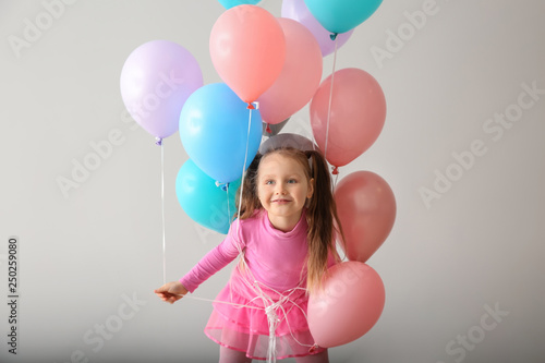 Cute little girl with balloons on white background