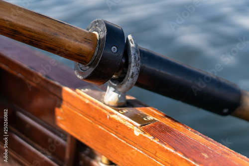 Closeup photo of wooden paddle attached to boat used for rowing in the water, lake Bled on a sunny day