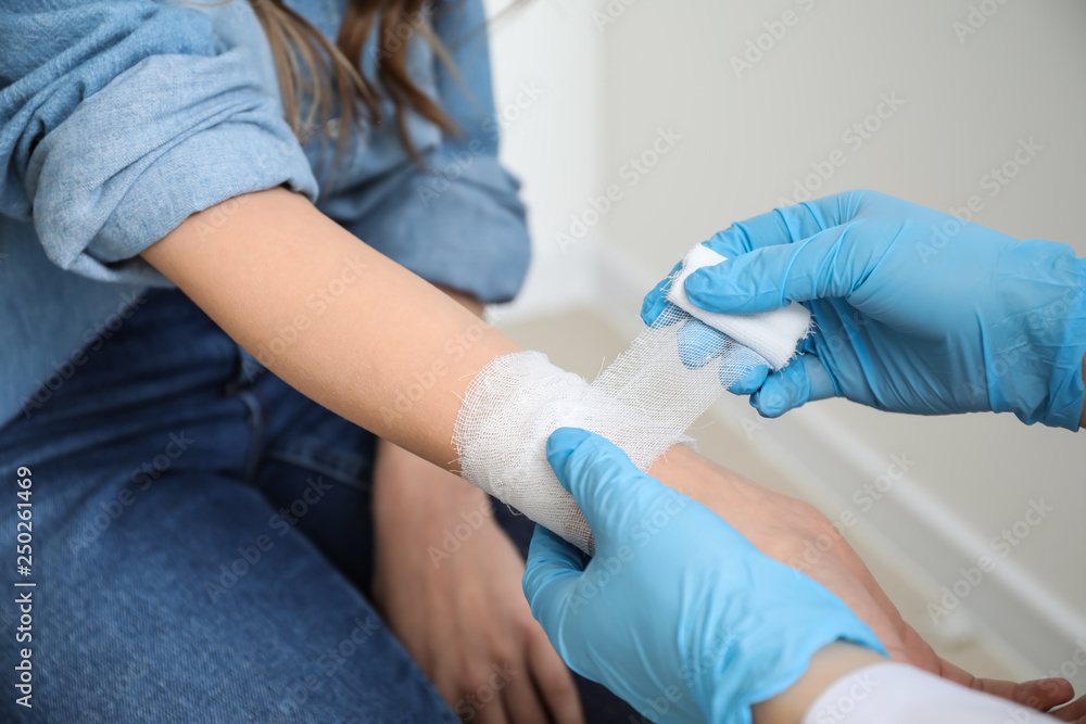 Doctor applying bandage onto wrist of young woman, closeup Doctor applying bandage onto wrist of young woman, closeup