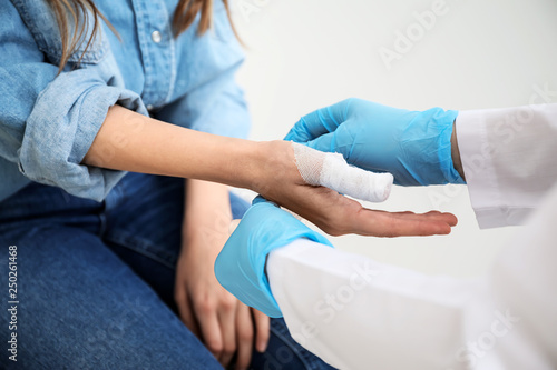 Doctor applying bandage onto finger of young woman, closeup © Pixel-Shot