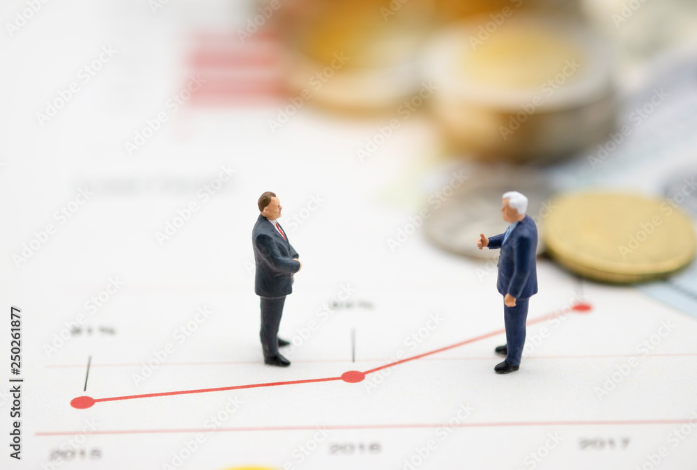 Miniature business men discuss on line chart of business growth .Copy space and business concept. -Image. Miniature business men discuss on line chart of business growth .Copy space and business concept. -Image.