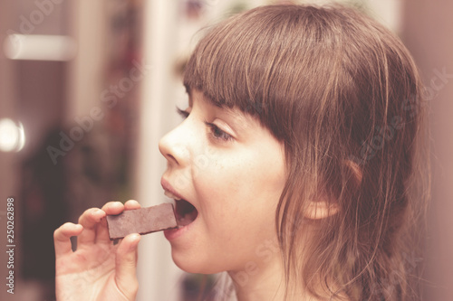 The girl with great pleasure is going to eat a sweet chocolate.