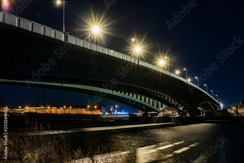Under a large bridge at night, a massive bridge construction at night, minna todenhagen bridge at night