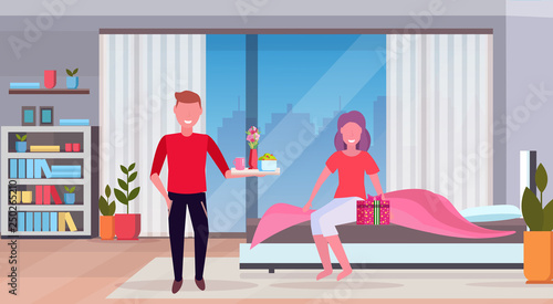 man bringing breakfast for his woman in bed happy 8 march womens day concept husband making surprise to wife modern bedroom interior full length flat horizontal © mast3r