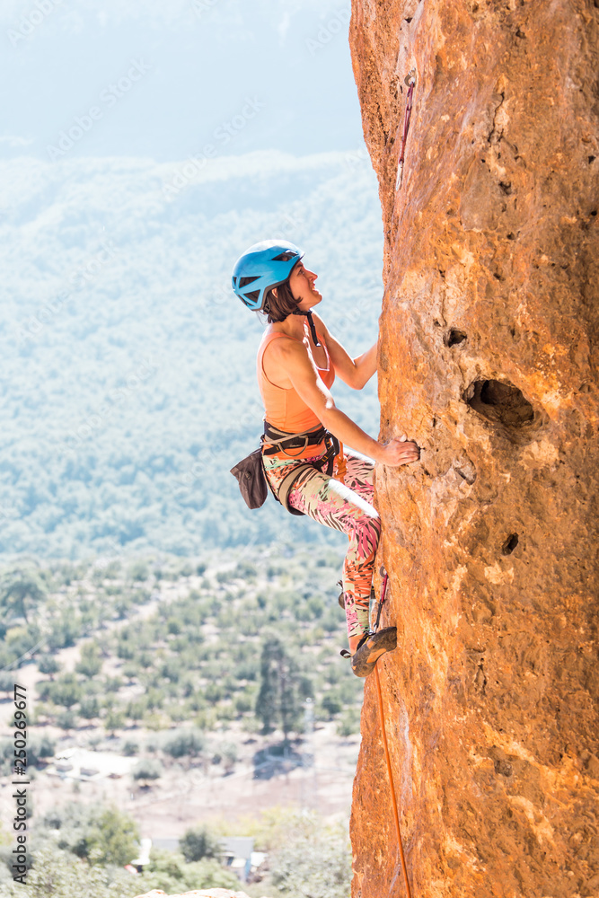Fototapeta premium A girl in a helmet climbs a rock.