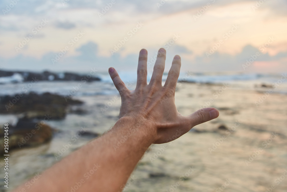 the guy reaches out to the clouds. The guy pulls his hand to the sea