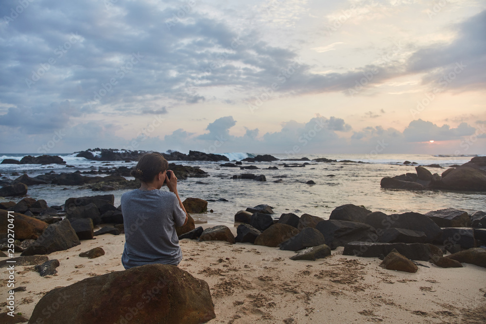 a young girl takes pictures of the sunset. Indian Ocean. 