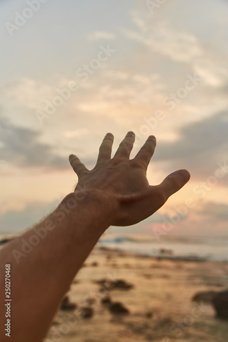 the guy reaches out to the clouds. The guy pulls his hand to the sea