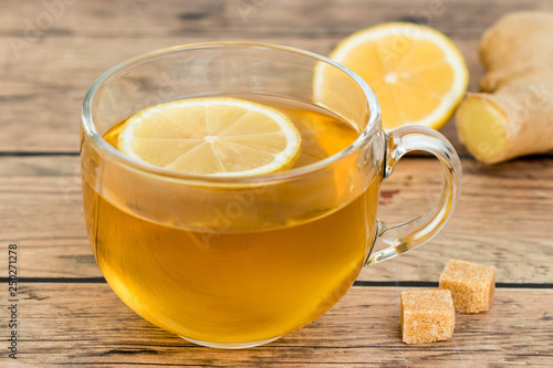 Ginger and lemon tea in glass mug and brown sugar. Healthy and energizing refreshment.
