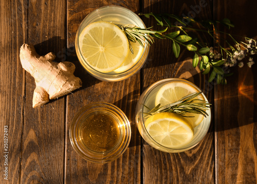 Glasses of fresh lemonade, honey and ginger on wooden table