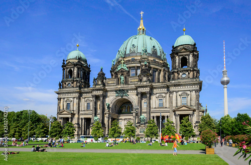Obraz na płótnie Touristen sonnen sich bei schönstem Sommerwetter auf der grünen Wiese vor dem Berliner Dom mit dem Berliner Fernsehturm im Hintergrund w salonie