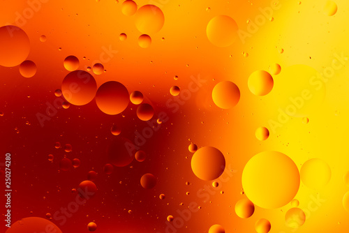 orange gradient oily drops circling in water with colorful background, close-up 