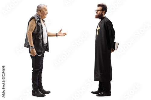 Mature male punker in a leather vest talking to a priest