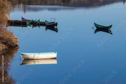 Small wooden boats with their reflection in the calm waters of the Tagus river, in ConstÃ¢ncia, Portugal. photo