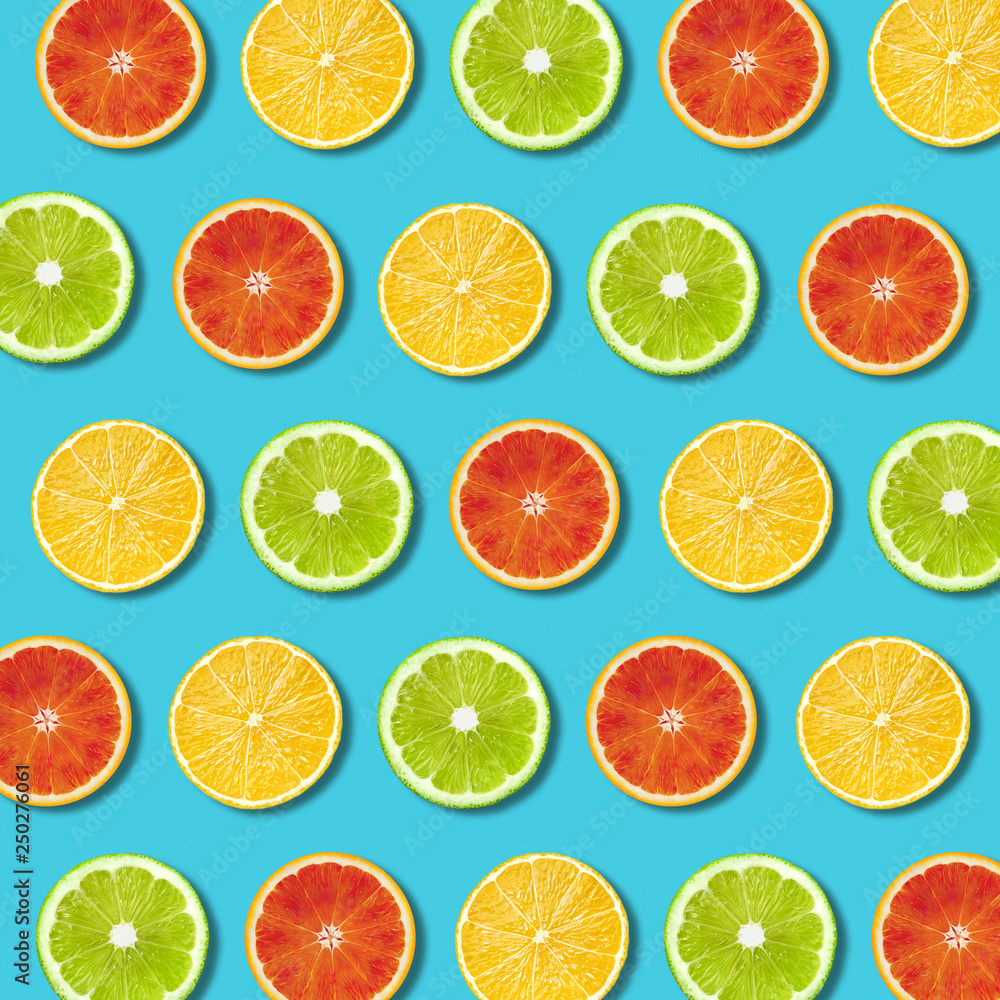 Vibrant red orange and green lime lemon slices pattern on turquoise color background. Minimal flat lay top view food texture 