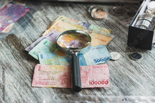 Different collector coins in the box, banknotes and magnifying glass