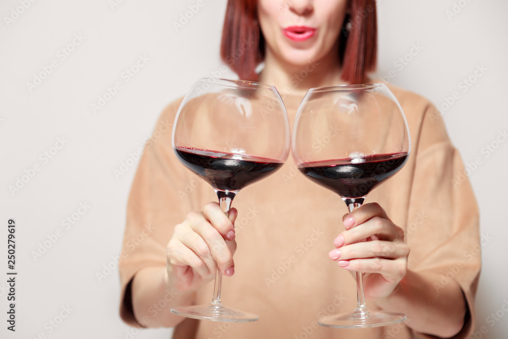 Redhaired girl sommelier on white background and hold with two glasses of red wine. Concept alcoholism, alcohol addiction, bad habit, collection rare wine, blind degustation Redhaired girl sommelier on white background and hold with two glasses of red wine. Concept alcoholism, alcohol addiction, bad habit, collection rare wine, blind degustation