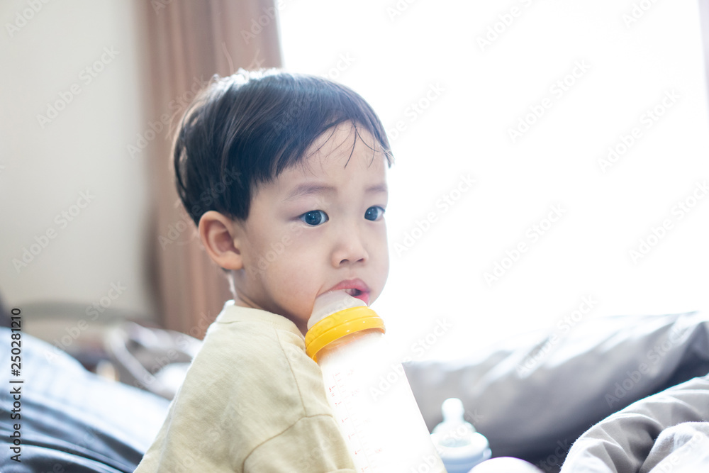 kid is sucking a bottle of milk in the morning while watching TV in the bed in the bedroom. kid is sucking a bottle of milk in the morning while watching TV in the bed in the bedroom.