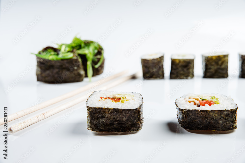Two chopsticks, sushi and rolls on white background Two chopsticks, sushi and rolls on white background