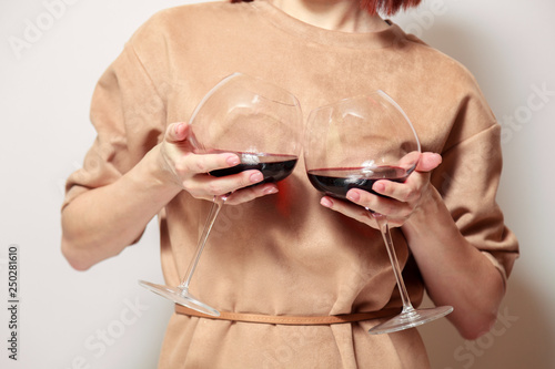 Young cute red haired woman sommelier on white background smile  hold two glasses red wine like a boobs. Concept alcoholism  alcohol addiction  bad habit  collection great rare wines  winelover