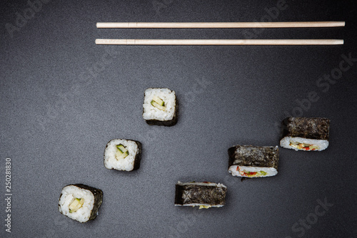 Two chopsticks, sushi and rolls on black background