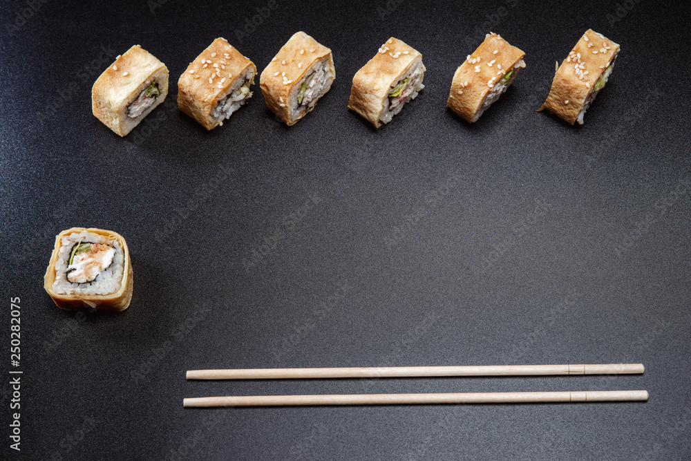 Two chopsticks, sushi and rolls on black background Two chopsticks, sushi and rolls on black background
